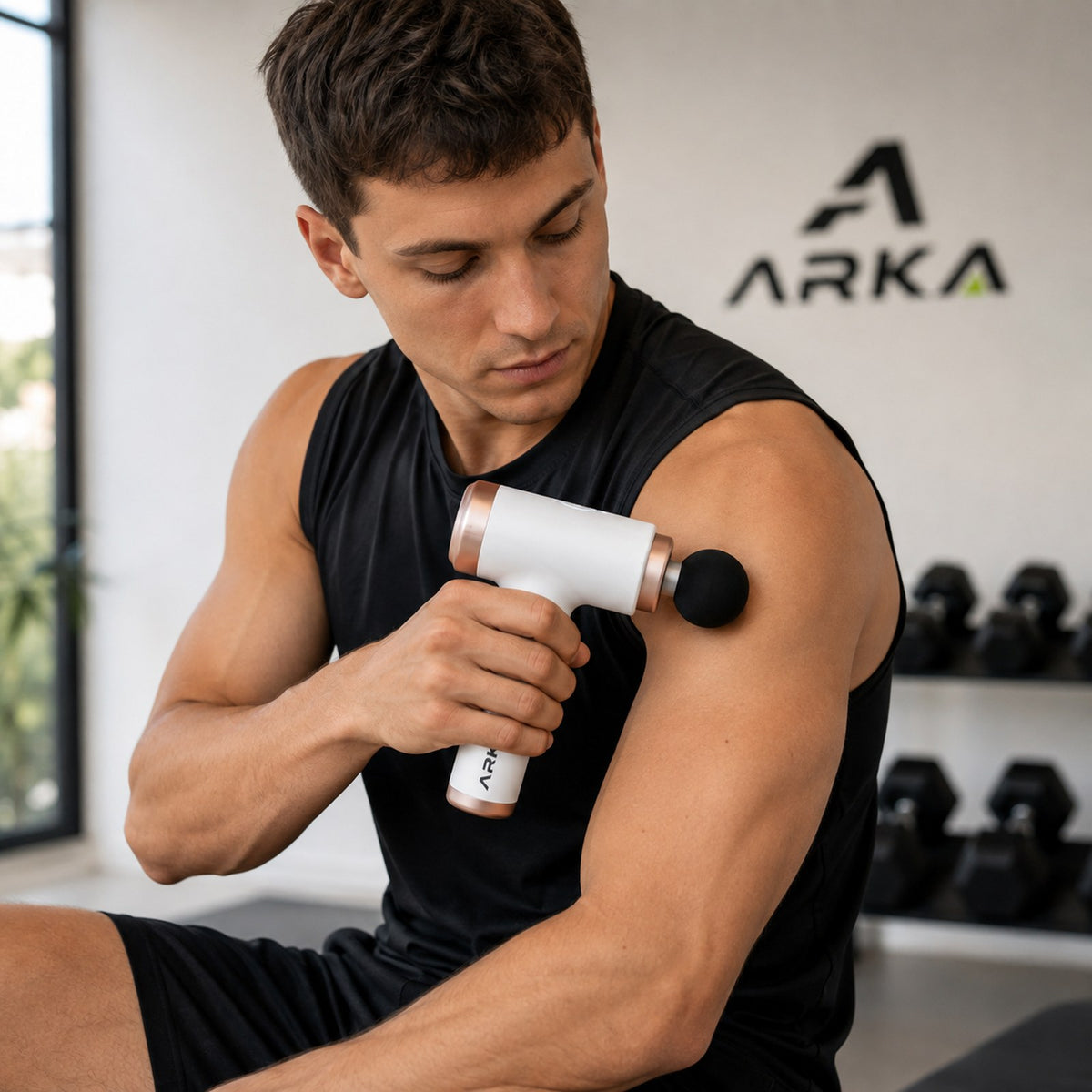 Hombre usando la pistola masajeadora Arka en el hombro en el gimnasio